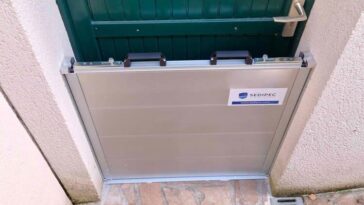 Barrière anti-inondation en aluminium installée devant une porte d'entrée de maison