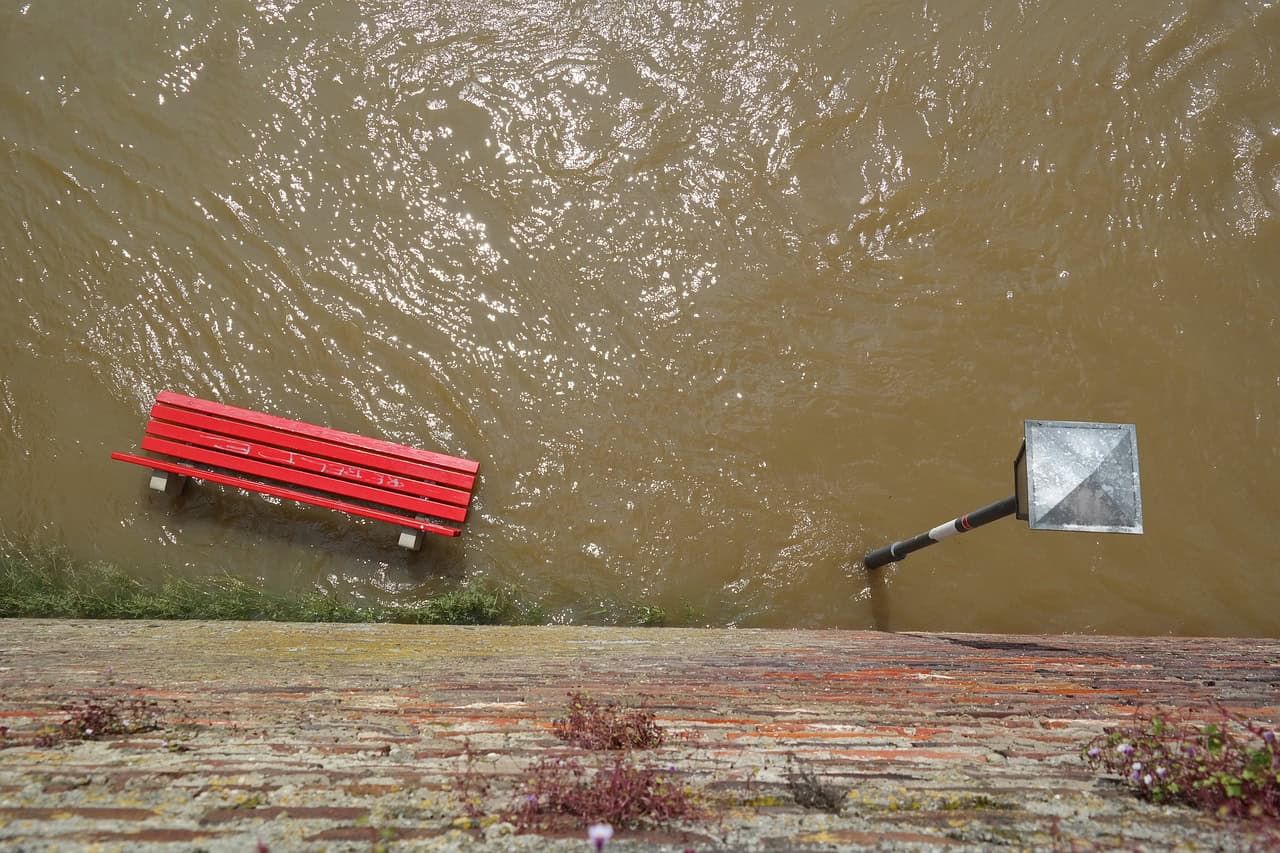 Photographie d'une inondation avec un banc rouge et un lampadaire sous l'eau