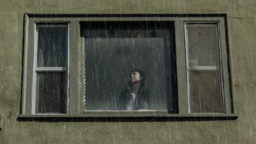 Personne à une fenêtre qui regarde la pluie