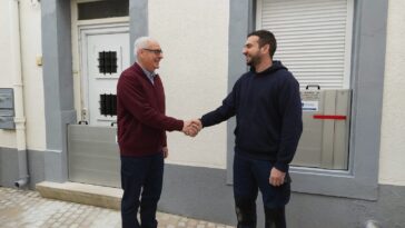 Un particulier âgé serre la main du poseur après la pose de batardeaux anti-inondation sur sa porte et fenêtre, installés par SEDIPEC et Floody.