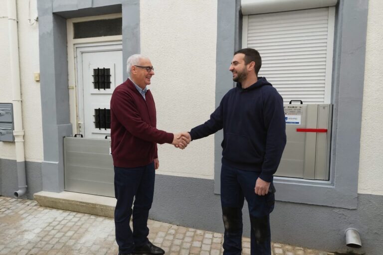 Un particulier âgé serre la main du poseur après la pose de batardeaux anti-inondation sur sa porte et fenêtre, installés par SEDIPEC et Floody.