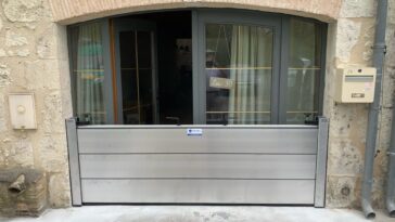 Batardeau amovible en aluminium installé devant une porte-fenêtre pour protéger une maison des inondations.