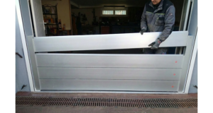 Technicien installant les lames d’un batardeau amovible en aluminium dans l’ouverture d’un garage pour se protéger des inondations