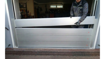 Technicien installant les lames d’un batardeau amovible en aluminium dans l’ouverture d’un garage pour se protéger des inondations