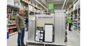Homme dans un magasin de bricolage consultant un rayon de batardeaux anti inondation rigides et gonflables pour choisir le bon modèle
