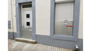 Façade de maison équipée de batardeaux autobloquants en aluminium devant la porte d’entrée et une fenêtre pour se protéger des inondations