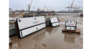 Plusieurs batardeaux gonflables Flowstop de tailles différentes posés sur palettes sur un site portuaire détrempé, prêts à servir de barrière anti inondation