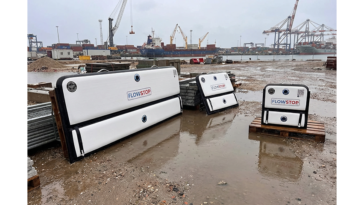 Plusieurs batardeaux gonflables Flowstop de tailles différentes posés sur palettes sur un site portuaire détrempé, prêts à servir de barrière anti inondation