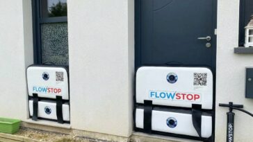 Système de batardeau gonflable FlowStop, installé sur une entrée et une fenêtre, montrant une protection étanche contre les crues avec pompe manuelle.
