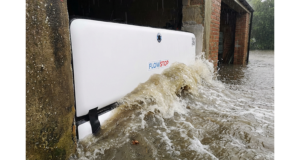 Batardeau gonflable Flowstop plaqué dans l’ouverture d’un garage, retenant une vague d’eau boueuse lors d’une inondation