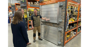 Vendeur en magasin de bricolage expliquant à deux clients les différents modèles de batardeaux en aluminium exposés au rayon barrières de protection anti inondation