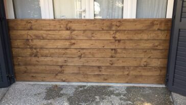 Barrière anti inondation fabriquée en planches de bois installée devant une baie vitrée pour protéger la maison des ruissellements