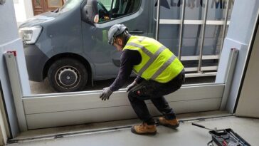Technicien en gilet de sécurité installant un batardeau en aluminium devant une porte de garage pour protéger le sous-sol des inondations